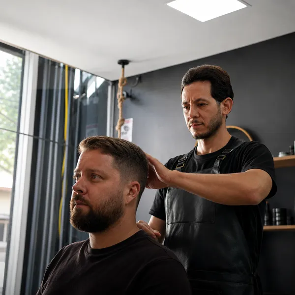Barbeiro da OLJ ajustando o corte de um cliente na barbearia