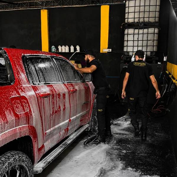 Equipe da OLJ lavando uma caminhonete vermelha coberta de espuma