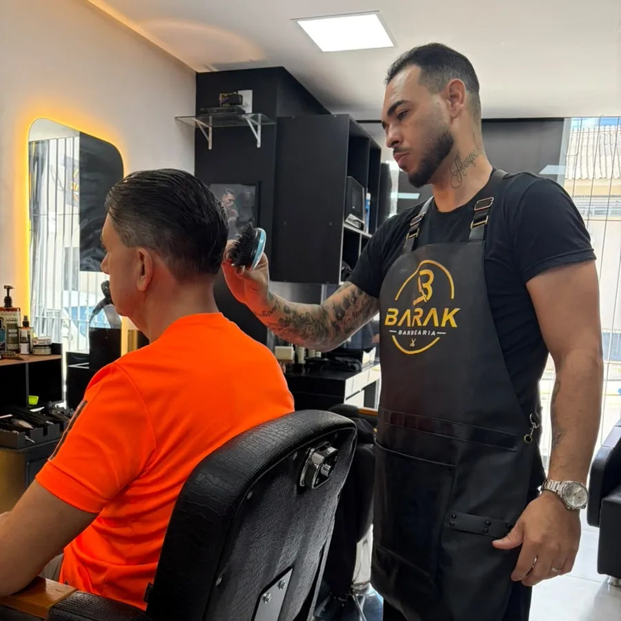 Barbeiro escovando o cabelo de um cliente na cadeira